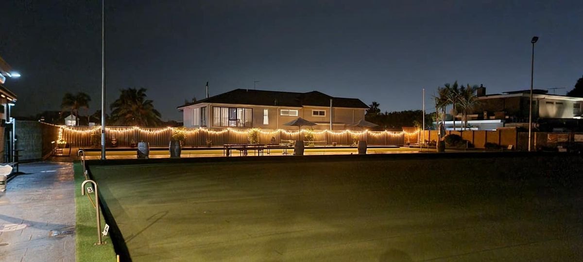 The green lit up for bowls by night, fairy lights along the clubhouse