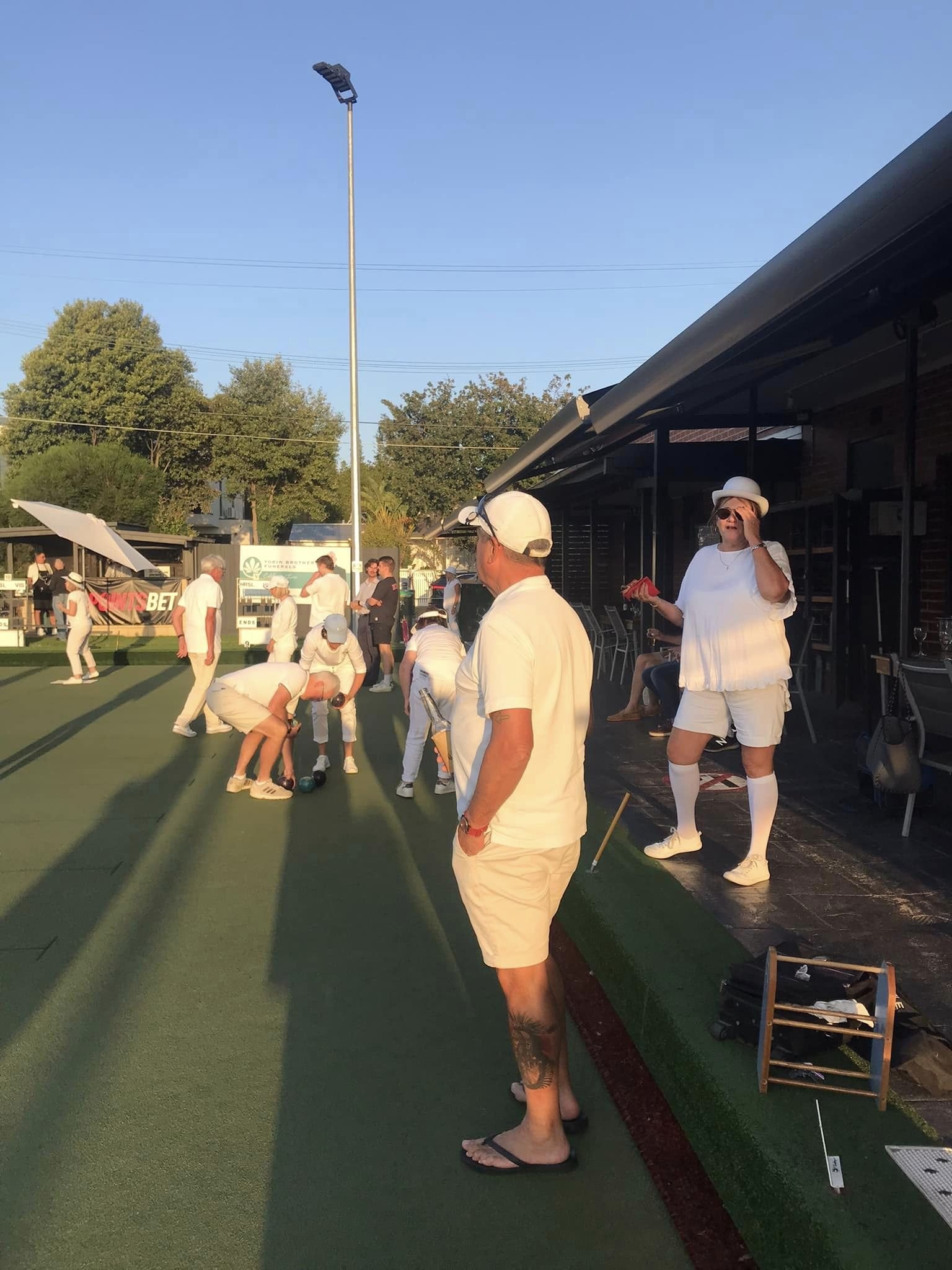 Bowlers in whites along the bank at dusk