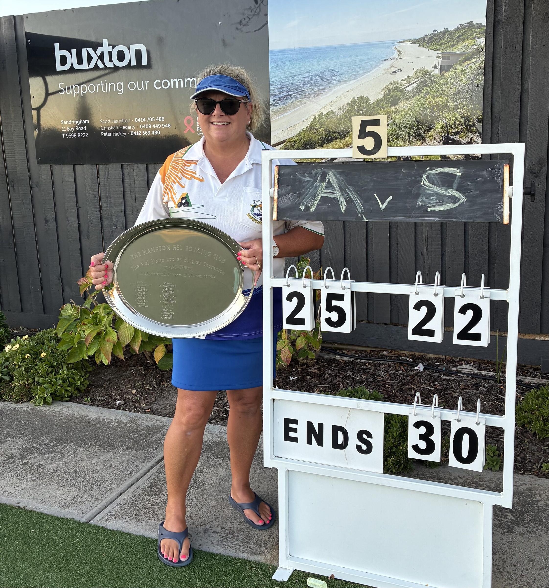 Annie Westhead with the Val Mann plate beside the scoreboard showing 25 to 22